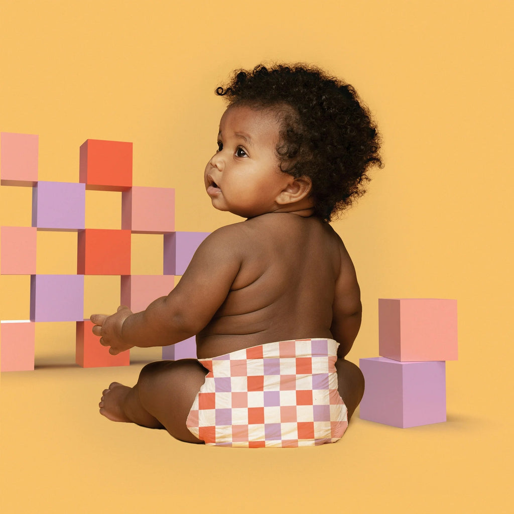 Baby wearing diaper, sitting with blocks.