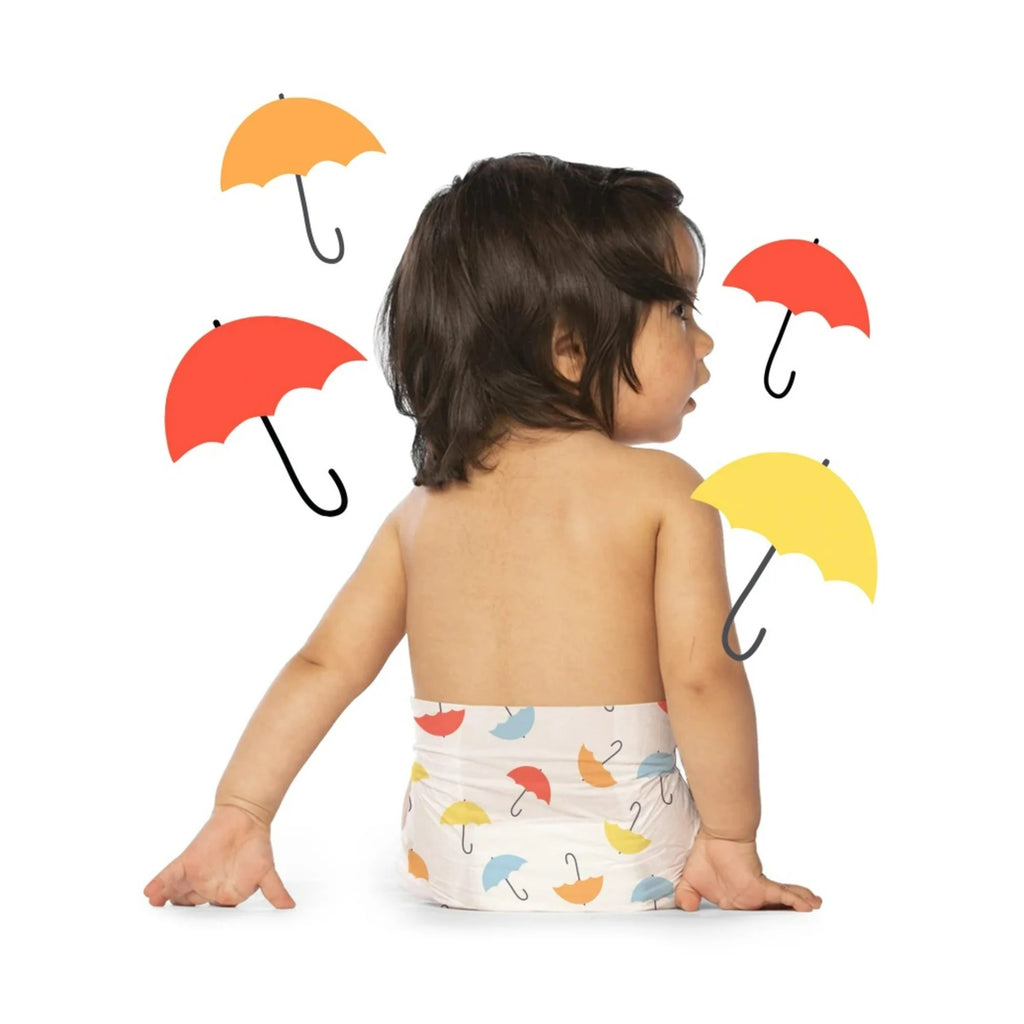 Baby with umbrella-patterned diaper, surrounded by umbrellas.