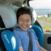 A young boy sitting in the back of his car.