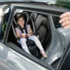 A child in the back of a car being pulled by a person.