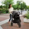 A woman pushing a stroller on the sidewalk.