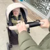 A man is holding the handle of a stroller