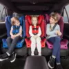 Three children sitting in the back of a car.