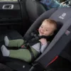 A baby sitting in the back of a car seat.