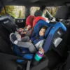 A child in the back of a car with two adults.