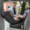 A man is putting his baby in the car seat.